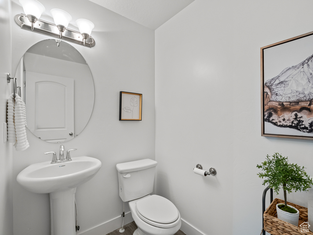Half bath featuring vaulted ceiling, toilet, a sink, and baseboards