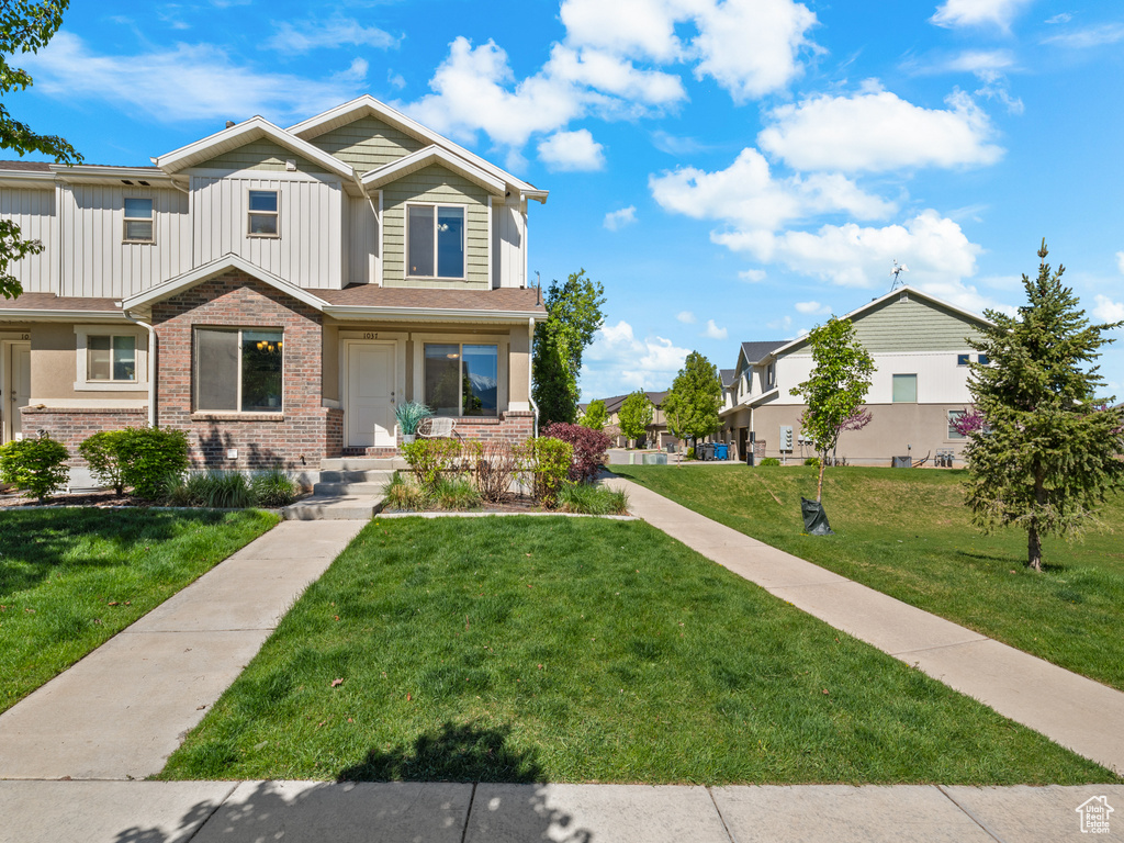 View of front of property featuring board and batten siding, brick siding, and a front yard