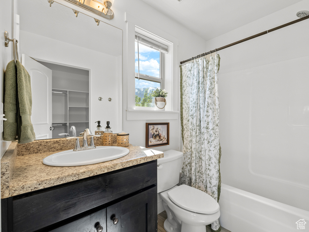 Bathroom with toilet, vanity, and shower / bath combo with shower curtain