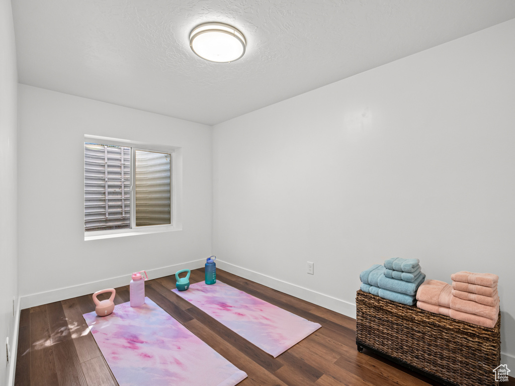 Interior space with a textured ceiling, baseboards, and wood finished floors