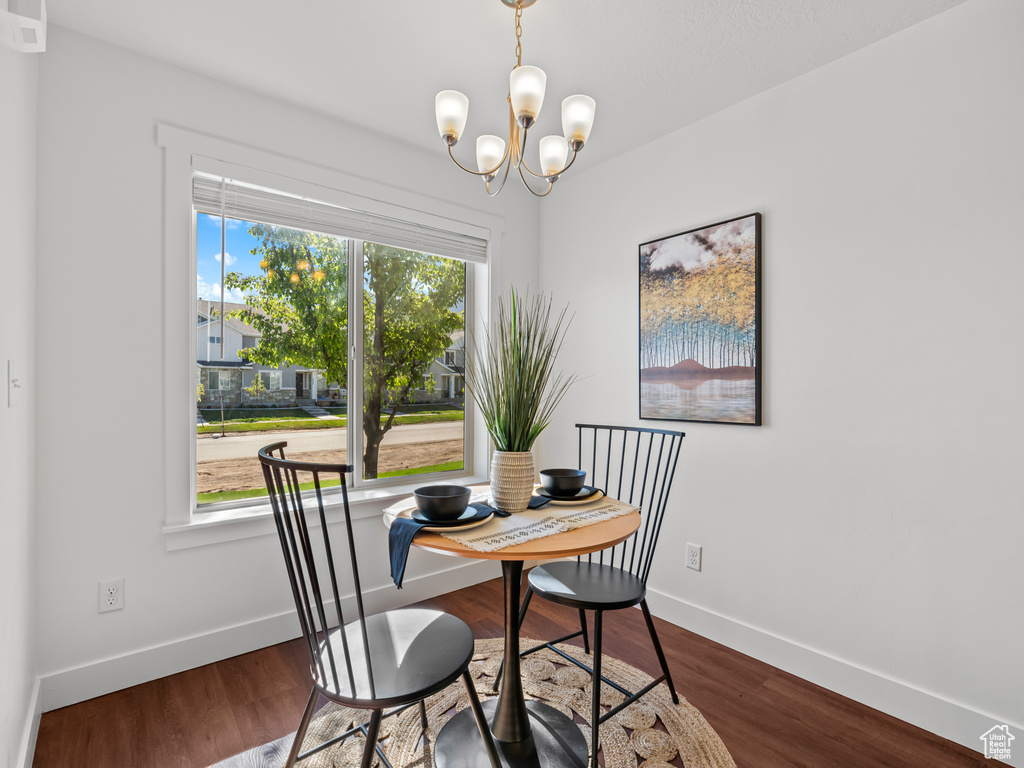 Dining area featuring dark wood-type flooring, baseboards, and a notable chandelier