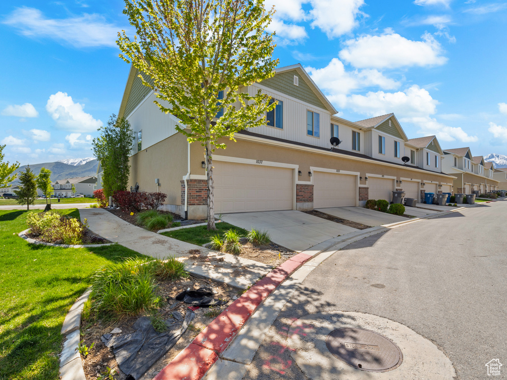 View of front of home with an attached garage, a mountain view, a residential view, concrete driveway, and brick siding