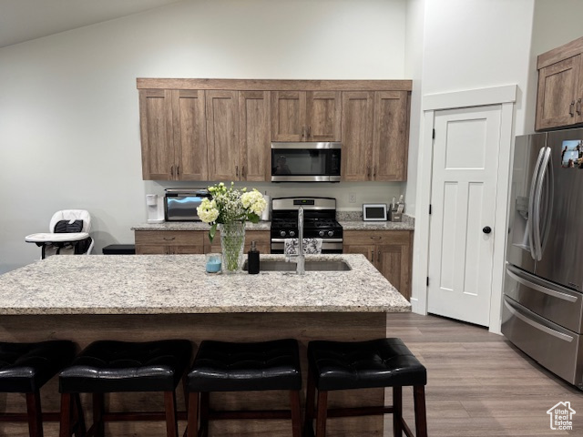 Kitchen with stainless steel appliances, a breakfast bar, light stone counters, and lofted ceiling