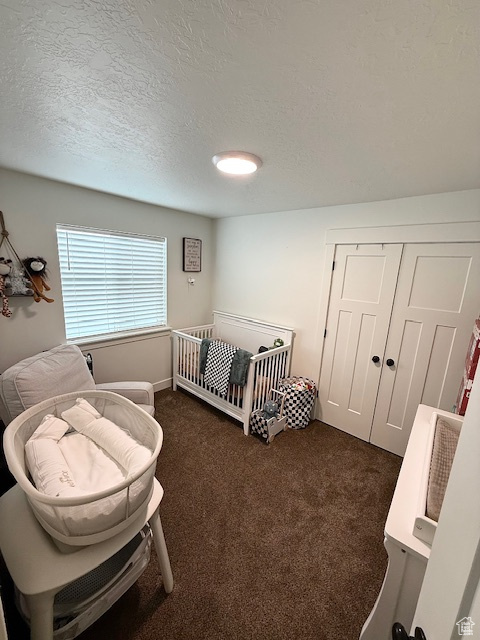 Bedroom featuring dark colored carpet, a textured ceiling, and a closet