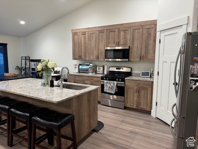 Kitchen featuring lofted ceiling, a breakfast bar, recessed lighting, a sink, and appliances with stainless steel finishes