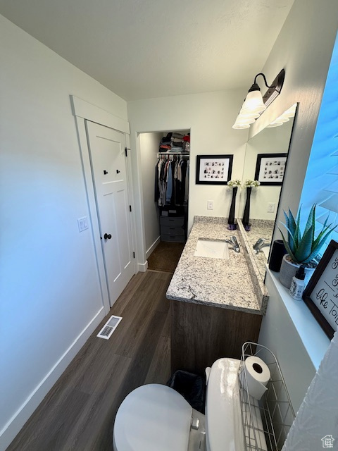 Bathroom featuring visible vents, vanity, wood finished floors, toilet, and baseboards