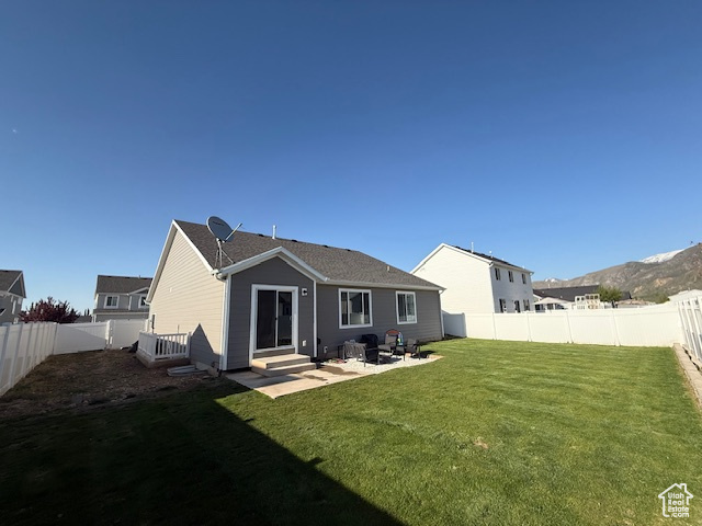 Rear view of house with a lawn, entry steps, a fenced backyard, and a patio area