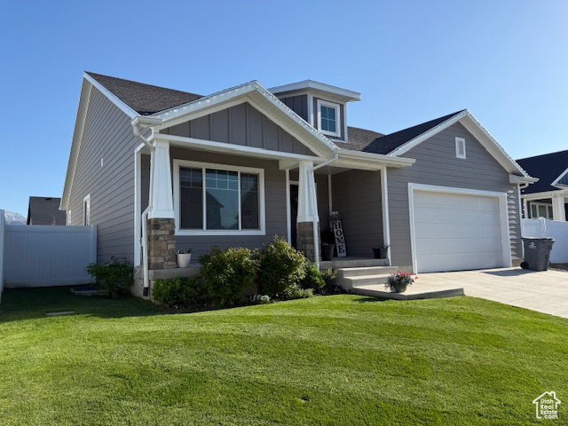 Craftsman house featuring concrete driveway, fence, a porch, and a front lawn