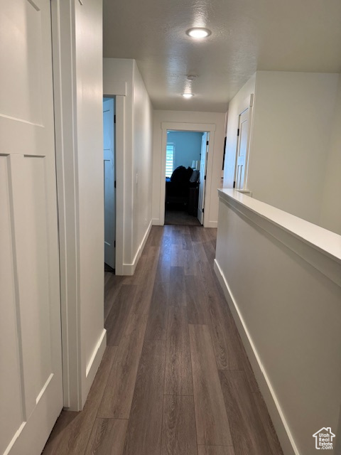 Hallway featuring baseboards and dark wood-style flooring
