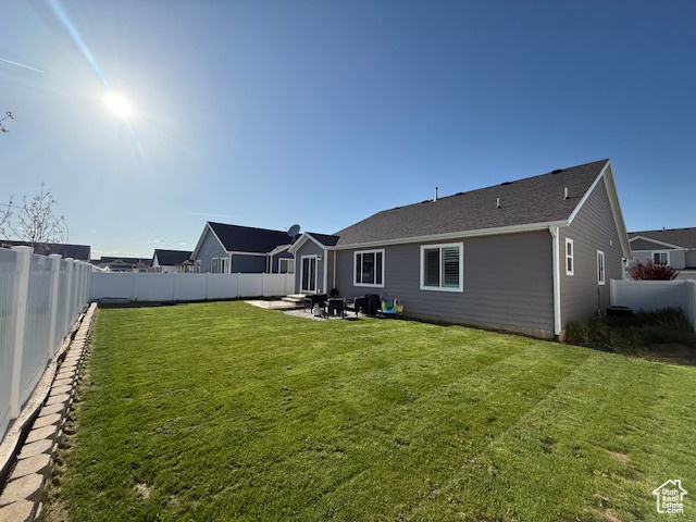 Rear view of house with a lawn, a fenced backyard, and a patio area