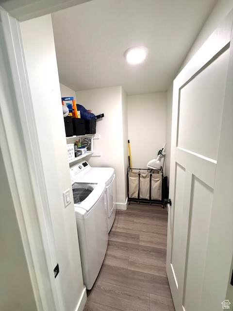 Clothes washing area featuring laundry area, light wood-style flooring, and washing machine and clothes dryer