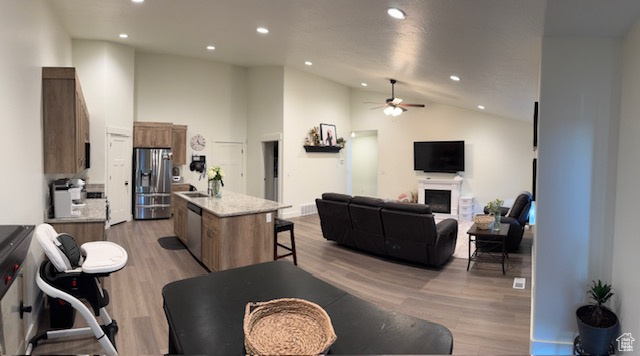 Living area with recessed lighting, light wood-style flooring, ceiling fan, and vaulted ceiling