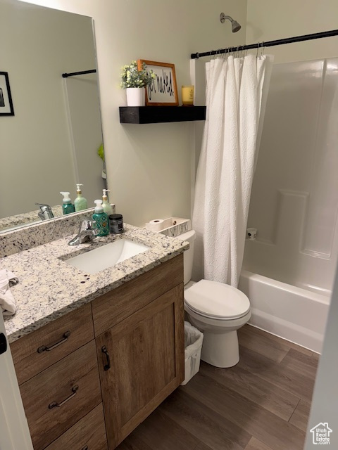 Full bathroom with vanity, shower / tub combo, wood finished floors, and toilet