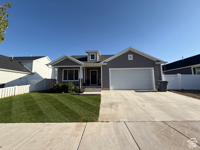 Craftsman inspired home featuring an attached garage, a front lawn, fence, and concrete driveway