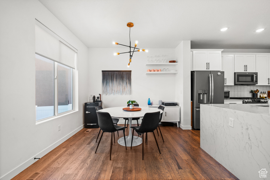 Kitchen featuring an inviting chandelier, stainless steel appliances, white cabinetry, and dark wood-style floors