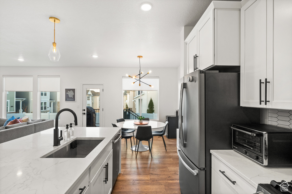 Kitchen featuring a sink, a chandelier, decorative light fixtures, and white cabinets