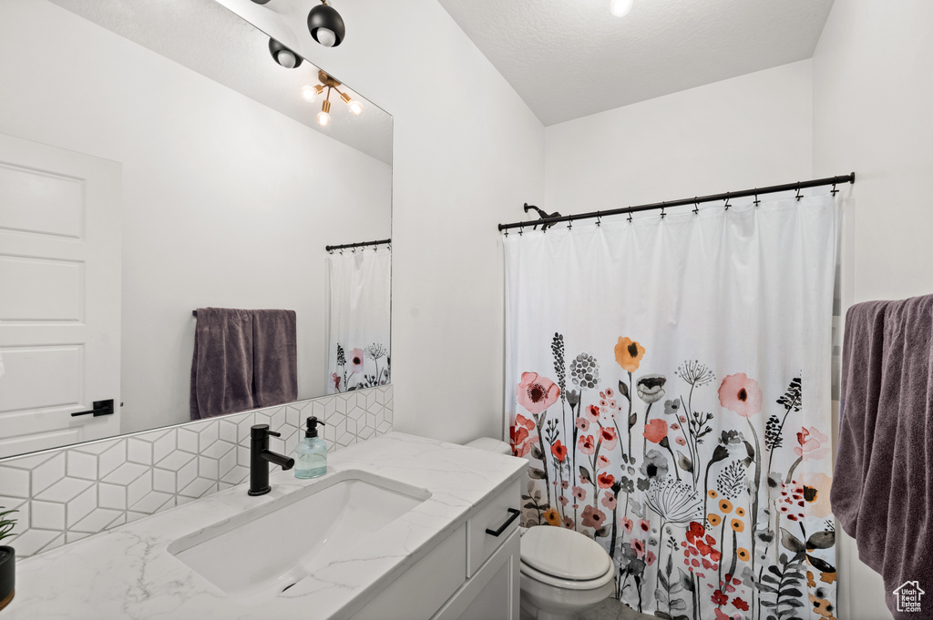 Full bathroom with backsplash, a shower with curtain, vanity, and toilet
