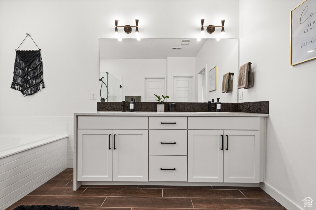 Bathroom featuring a sink, a shower, wood finish floors, double vanity, and a bath