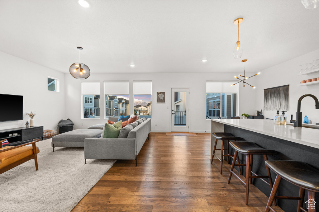 Living room with an inviting chandelier, dark wood-type flooring, and recessed lighting
