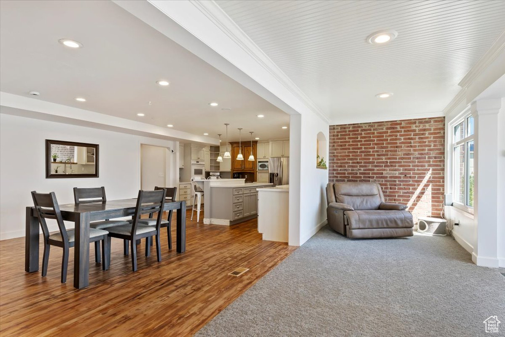 Dining space with crown molding, wood finished floors, baseboards, and recessed lighting