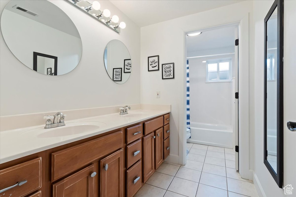 Full bath with a sink, double vanity, visible vents, and tile patterned floors