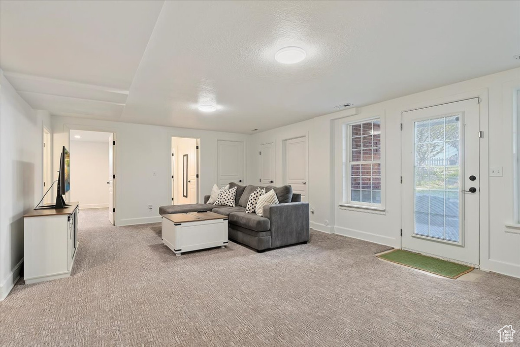 Living room featuring light colored carpet, a textured ceiling, and baseboards