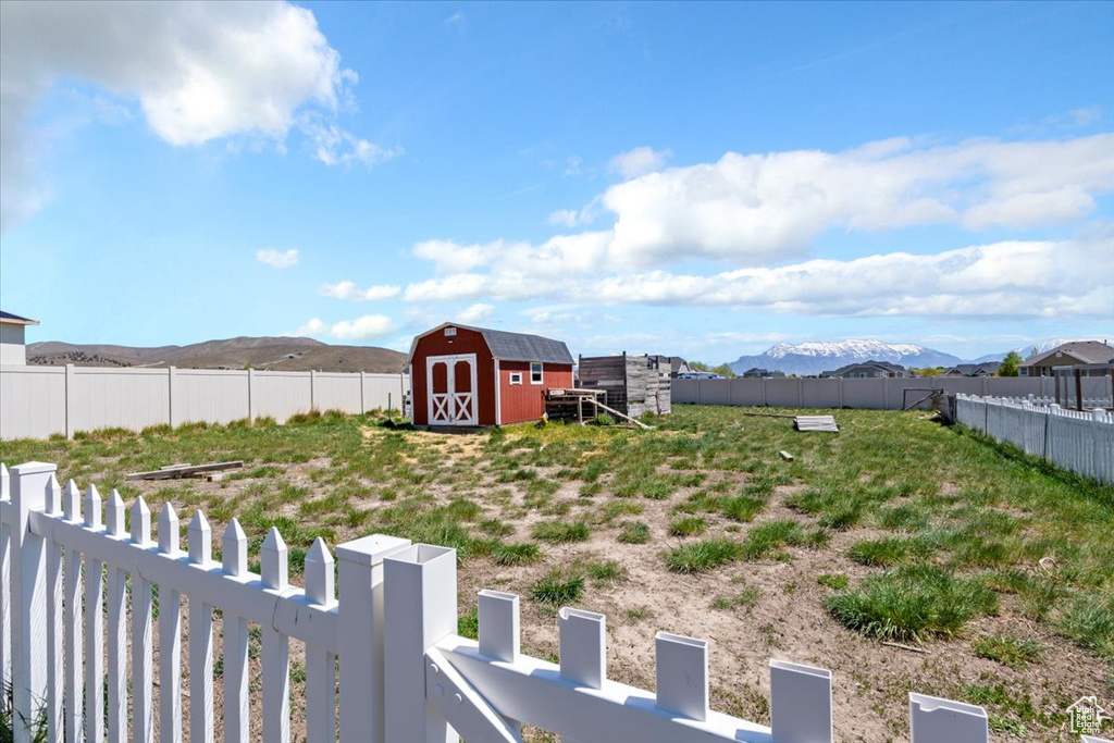 View of yard featuring a storage unit, a fenced backyard, a mountain view, and an outbuilding