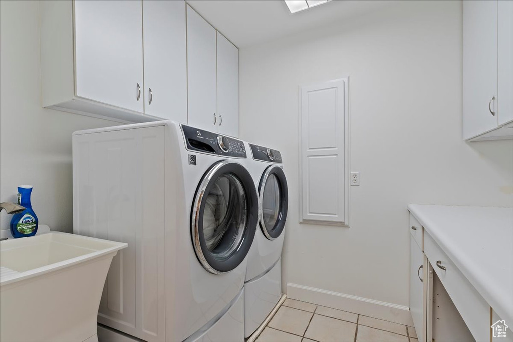 Laundry area with a sink, cabinet space, baseboards, independent washer and dryer, and light tile patterned flooring