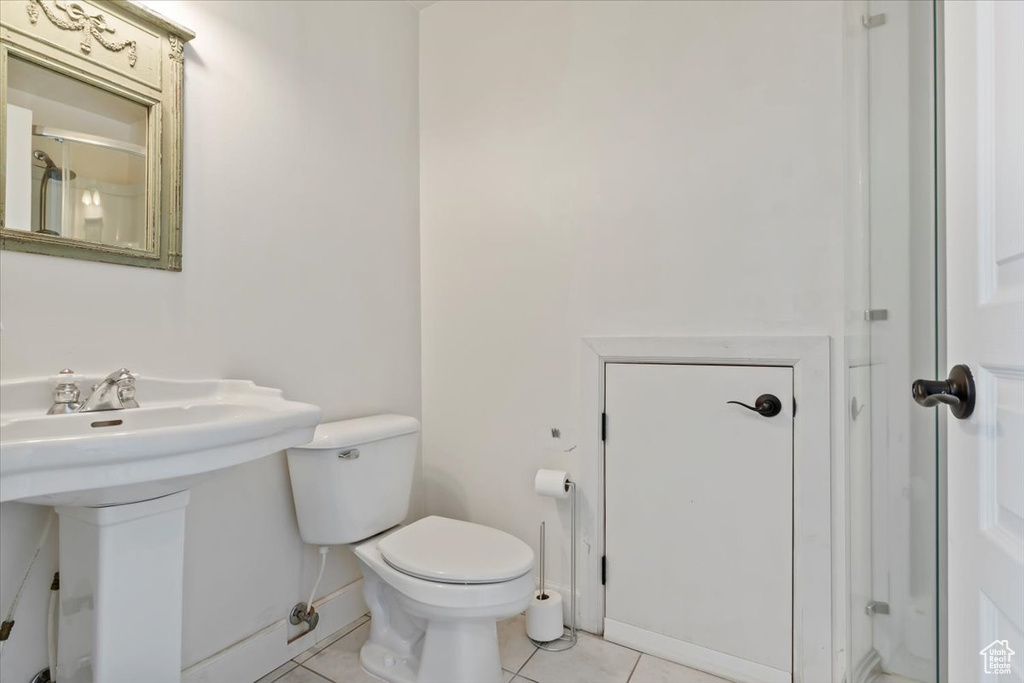 Bathroom featuring toilet, tile patterned flooring, and a sink
