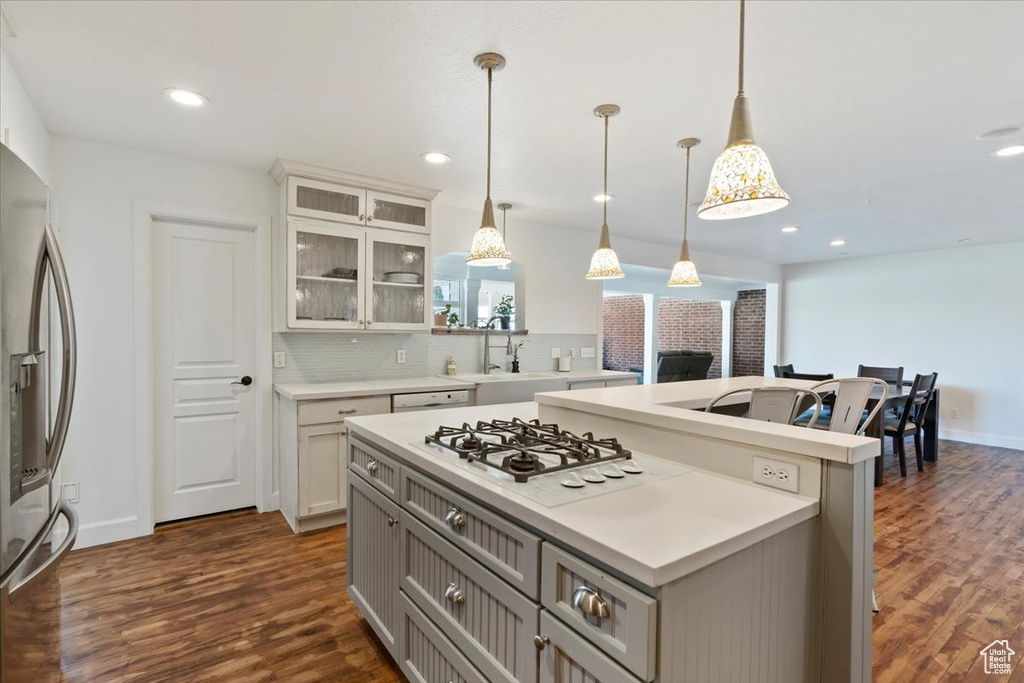 Kitchen featuring a center island, stainless steel fridge, white gas stovetop, dark wood-style flooring, and light countertops