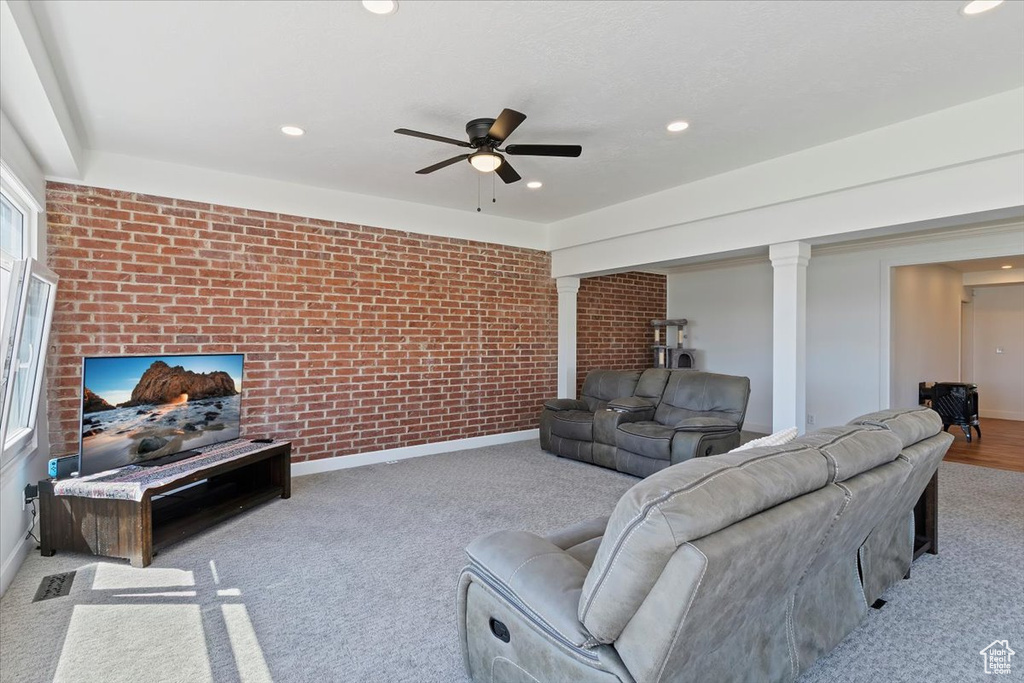 Carpeted living room with recessed lighting, a ceiling fan, ornate columns, and brick wall