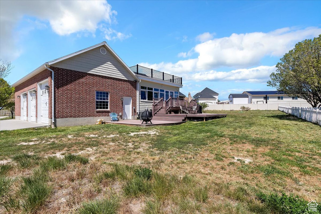 Back of house with a lawn, brick siding, fence, a garage, and concrete driveway