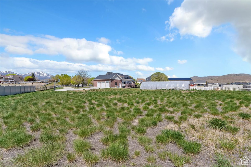 View of yard with an attached garage, a mountain view, and fence