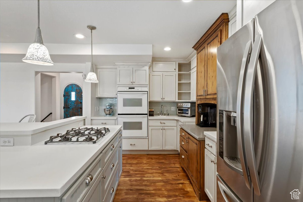 Kitchen with white appliances, tasteful backsplash, open shelves, light countertops, and dark wood-style floors