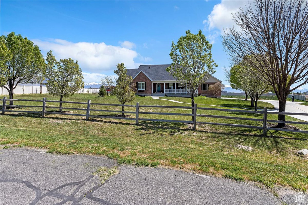 Ranch-style house featuring a front yard, brick siding, a fenced front yard, and covered porch