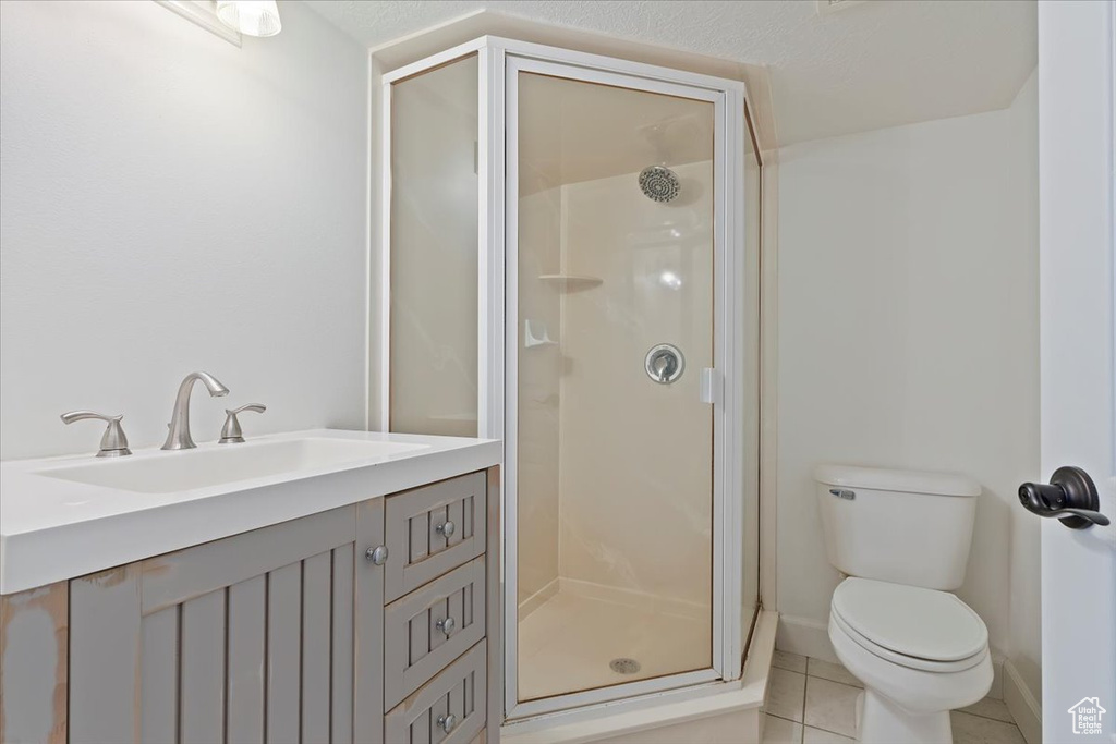 Bathroom with a stall shower, toilet, baseboards, tile patterned flooring, and vanity