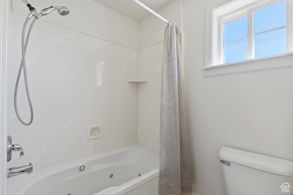 Bathroom with toilet and a combined bath / shower with jetted tub