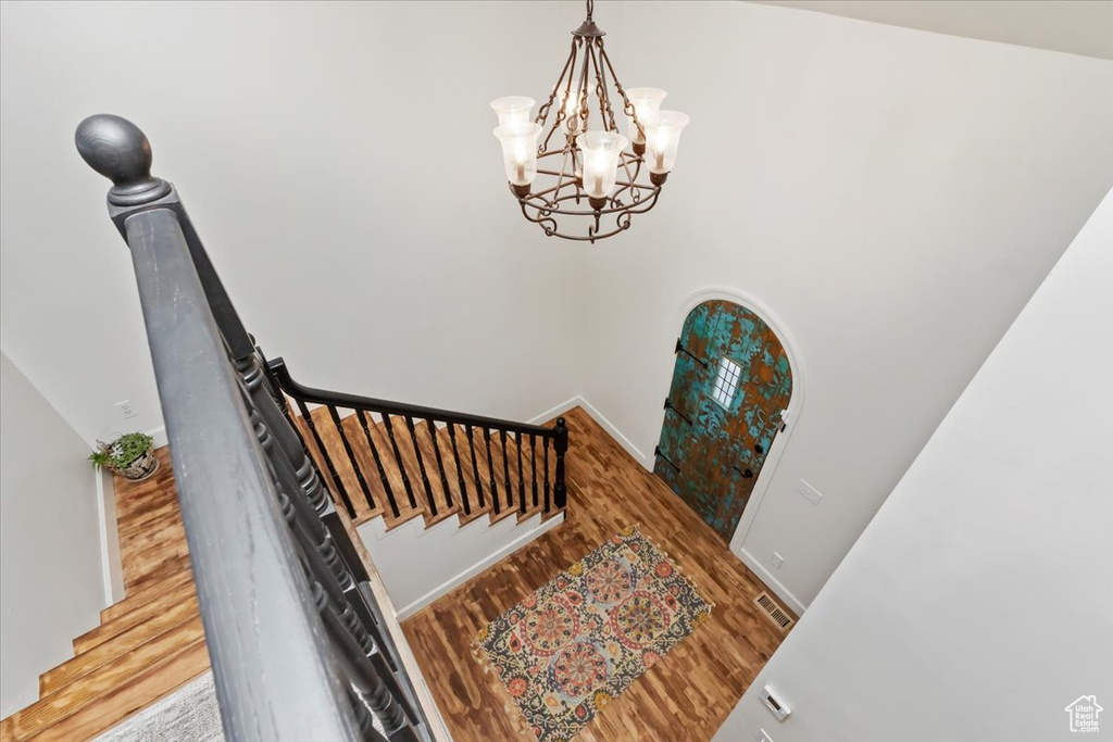 Stairway featuring an inviting chandelier, baseboards, visible vents, and wood finished floors