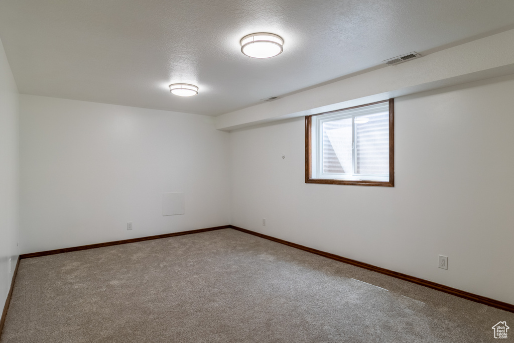 Carpeted spare room with visible vents, baseboards, and a textured ceiling