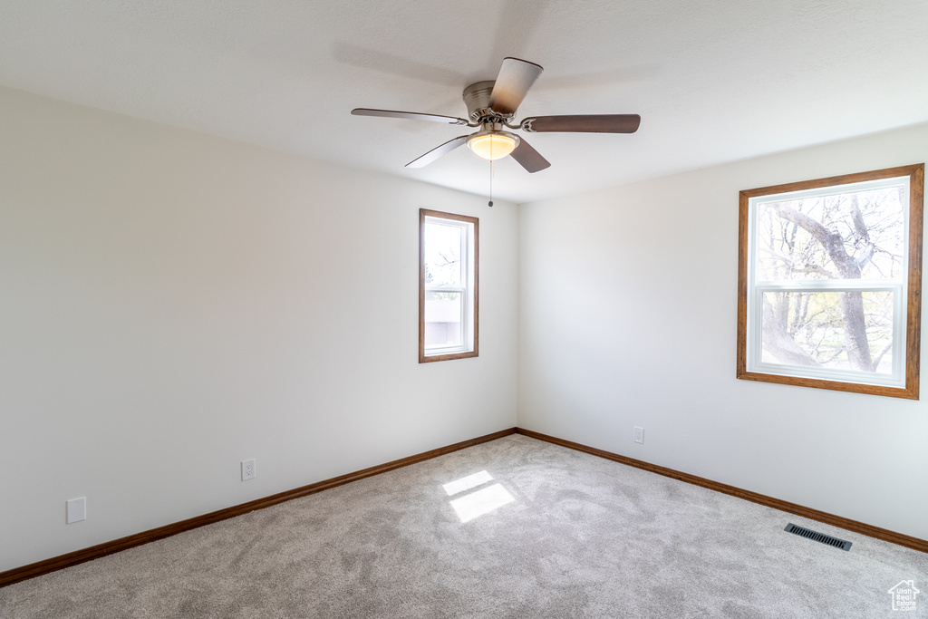 Carpeted empty room featuring visible vents, baseboards, and a ceiling fan
