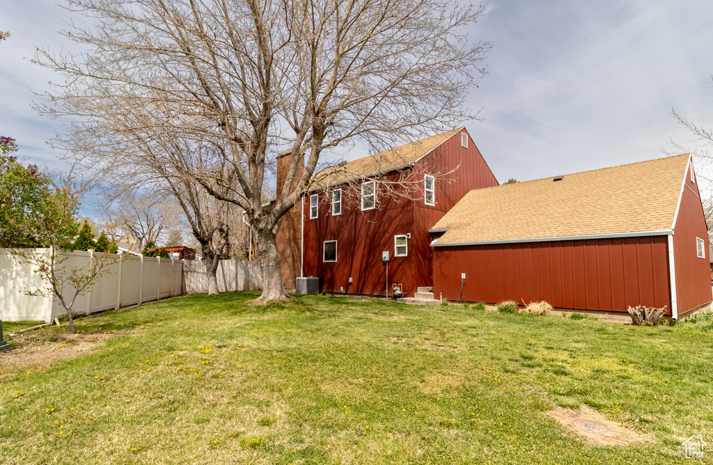 View of yard featuring central air condition unit and fence