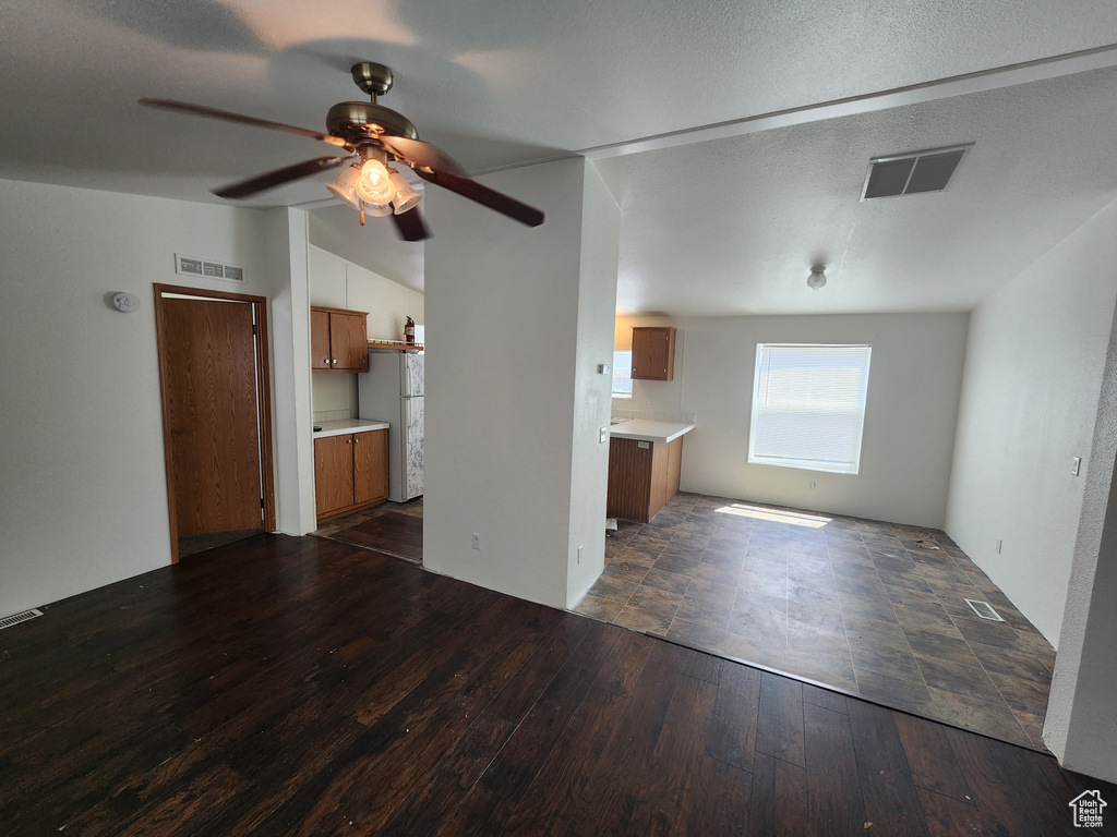 Unfurnished living room with lofted ceiling, ceiling fan, visible vents, and dark wood-type flooring