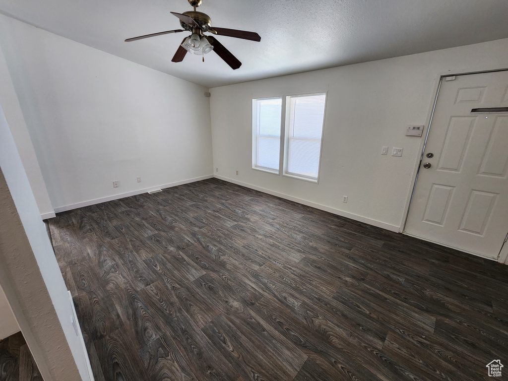 Unfurnished room featuring dark wood finished floors, a ceiling fan, and baseboards