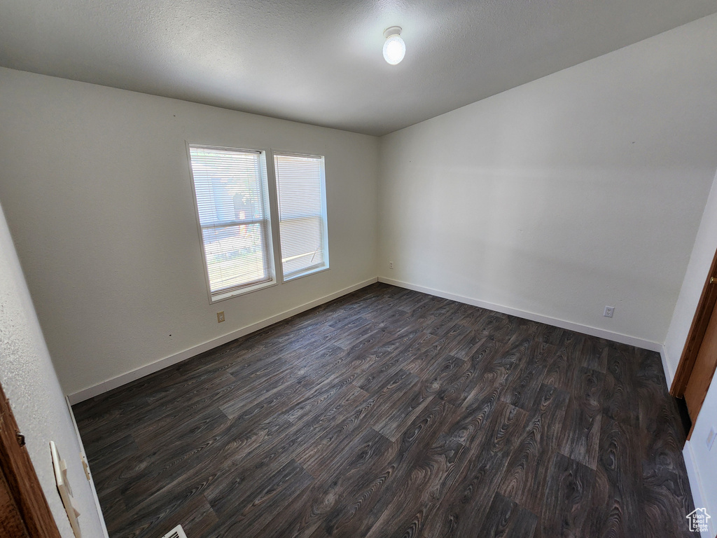 Spare room with dark wood-style floors and baseboards