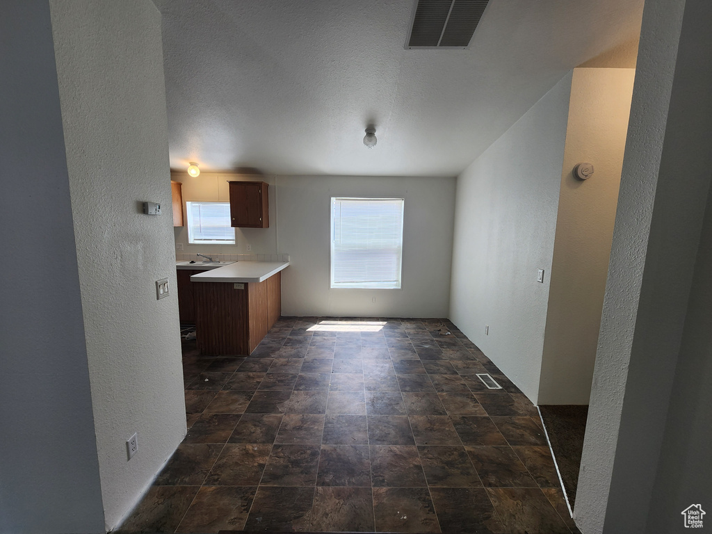 Unfurnished dining area featuring visible vents, a sink, stone finish floor, and a textured wall
