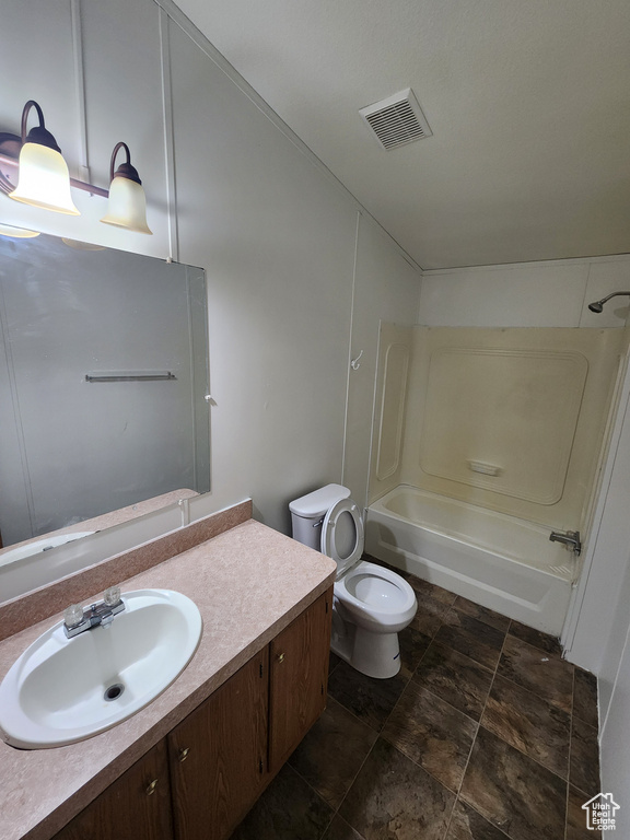 Full bath featuring toilet, bathtub / shower combination, stone finish flooring, visible vents, and vanity