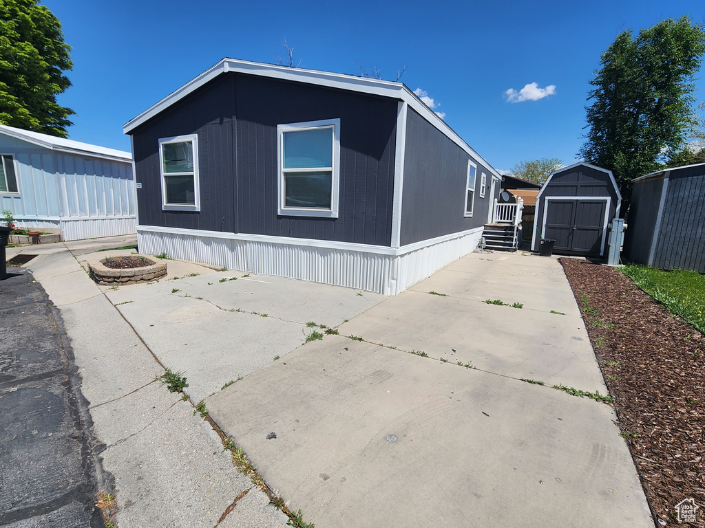 View of front facade with a storage shed, an outdoor structure, and a patio