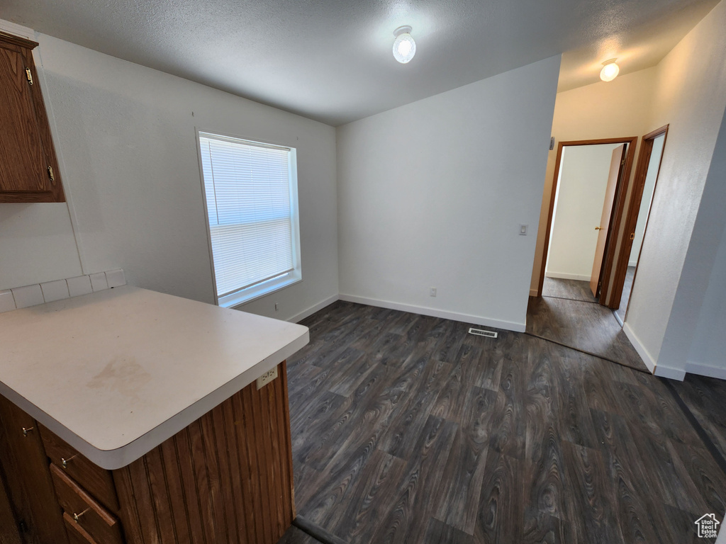 Unfurnished dining area with dark wood-type flooring and baseboards