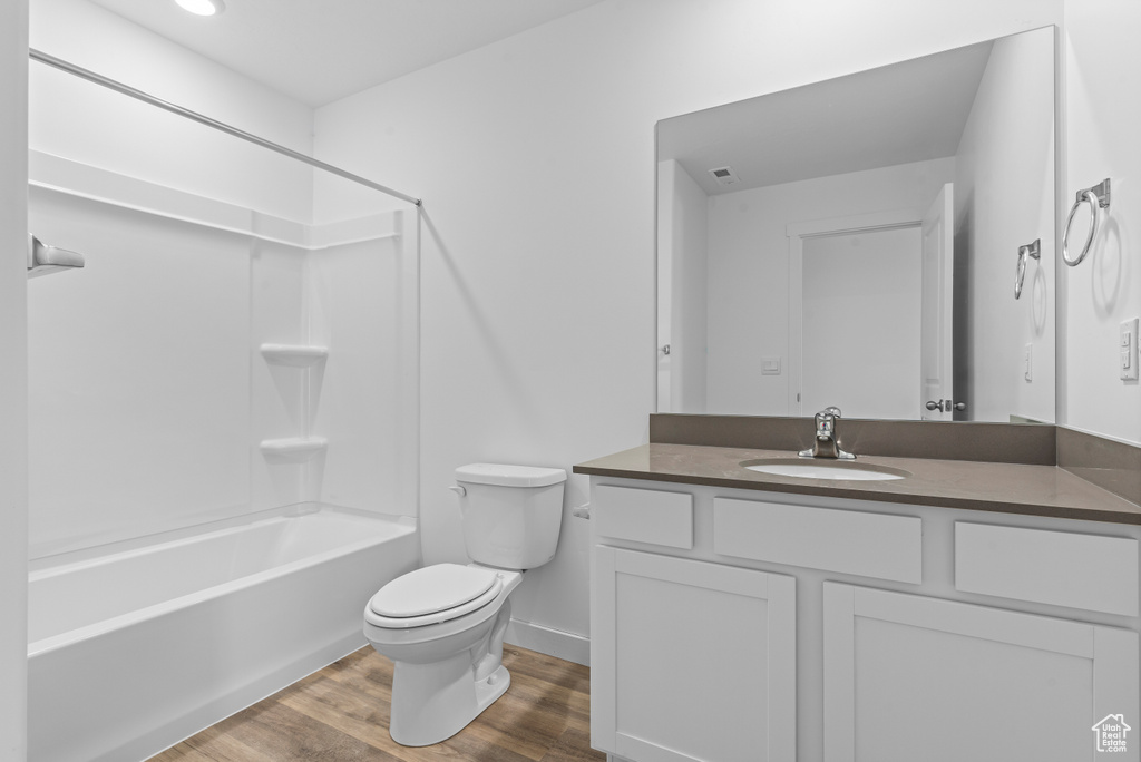 Full bath featuring toilet, wood finished floors, vanity, washtub / shower combination, and baseboards