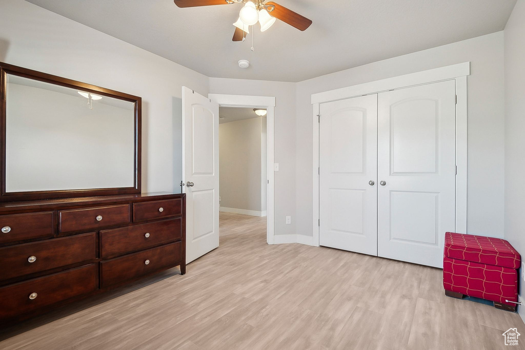 Unfurnished bedroom with baseboards, ceiling fan, light wood finished floors, and a closet